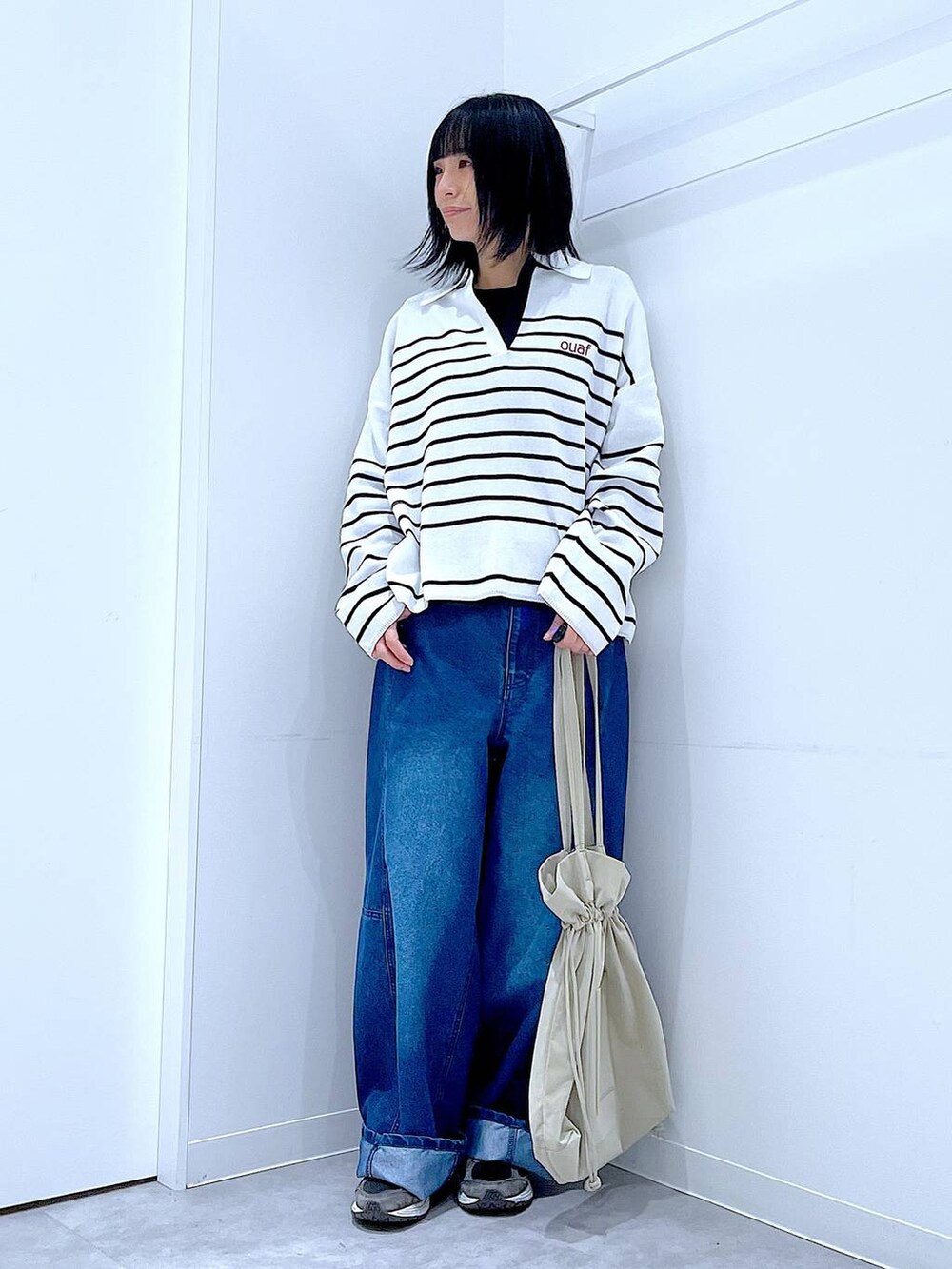 ブラック系のTシャツ/カットソー、ベージュ系のトートバッグ、ブルー系のデニムパンツを着用したレディースの冬コーディネートの2枚目の写真