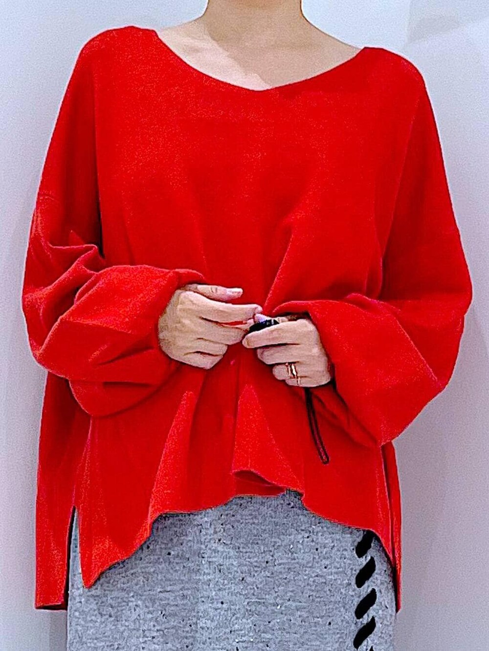 レッド系のニット/セーター、グレー系のスカート、ブラック系のブーツを着用したレディースの秋コーディネートの7枚目の写真