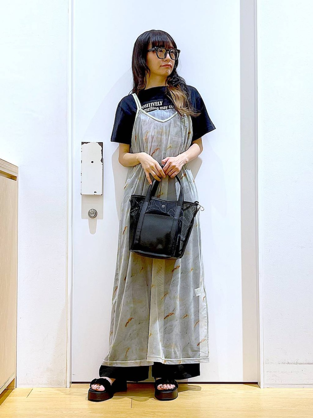 ブラック系のサンダル、ブラック系のトートバッグ、ベージュ系のワンピースを着用したレディースの夏コーディネートの2枚目の写真