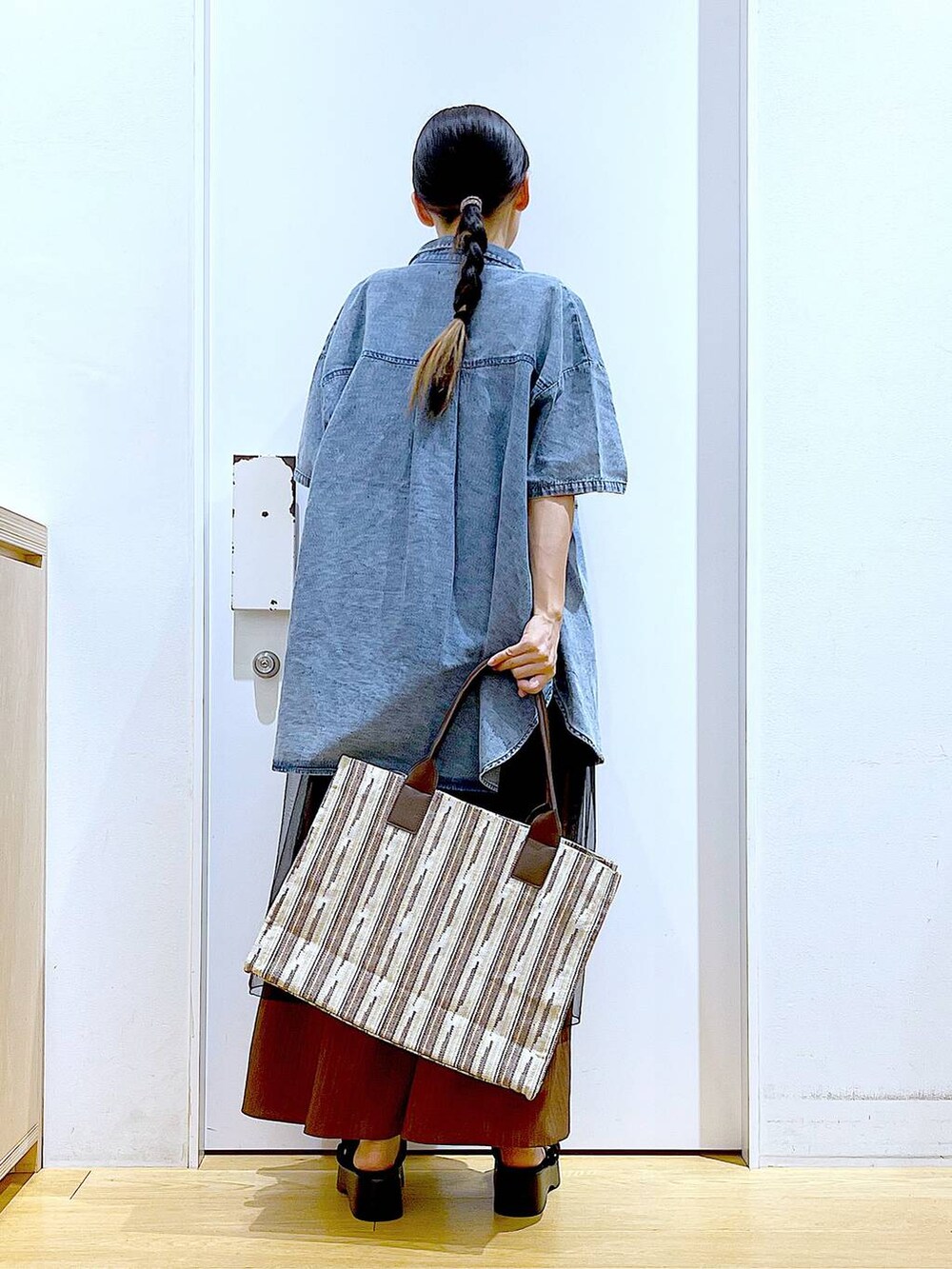 ブラック系のサンダル、ブラウン系のトートバッグ、ブラック系のワンピースを着用したレディースの夏コーディネートの5枚目の写真