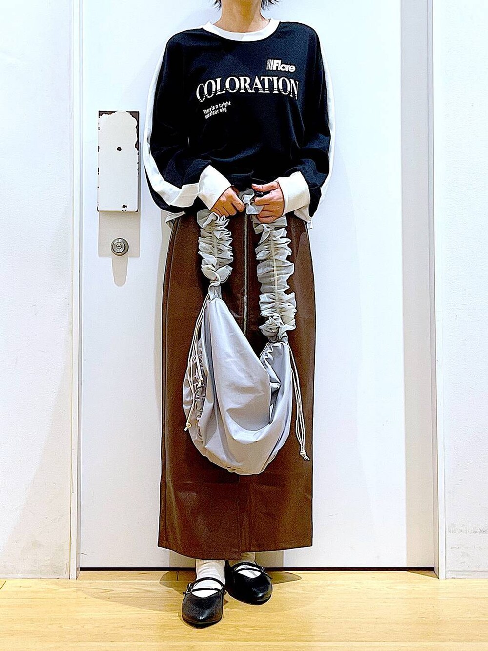 ブラウン系のスカート、ブラック系のパンプス、グレー系のショルダーバッグを着用したレディースの秋コーディネートの6枚目の写真