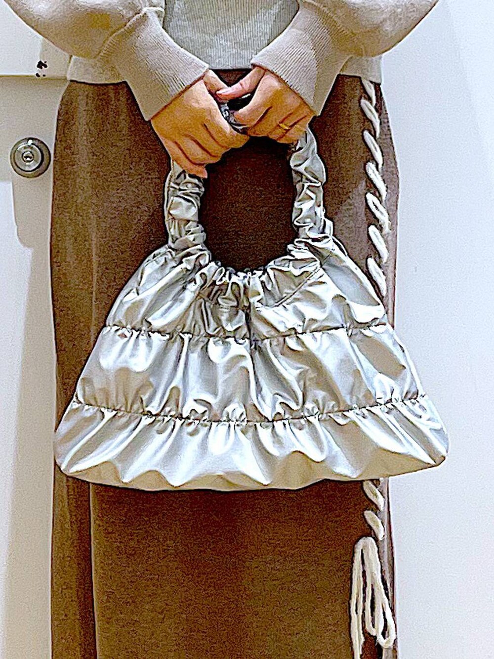 ブラック系のブーツ、ブラウン系のスカート、シルバー系のショルダーバッグを着用したレディースの冬コーディネートの9枚目の写真