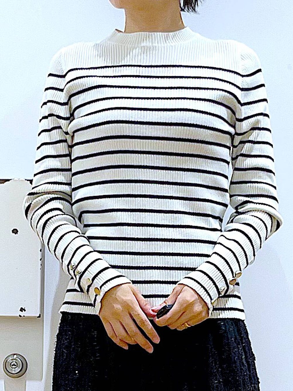 ホワイト系のニット/セーター、ブラック系のハンドバッグ、ブラック系のブーツを着用したレディースの秋コーディネートの7枚目の写真