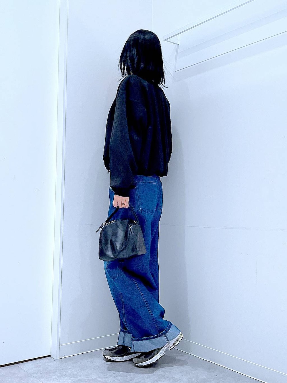 ブラック系のショルダーバッグ、ブルー系のデニムパンツ、ブラック系のスウェットを着用したレディースの春コーディネートの3枚目の写真