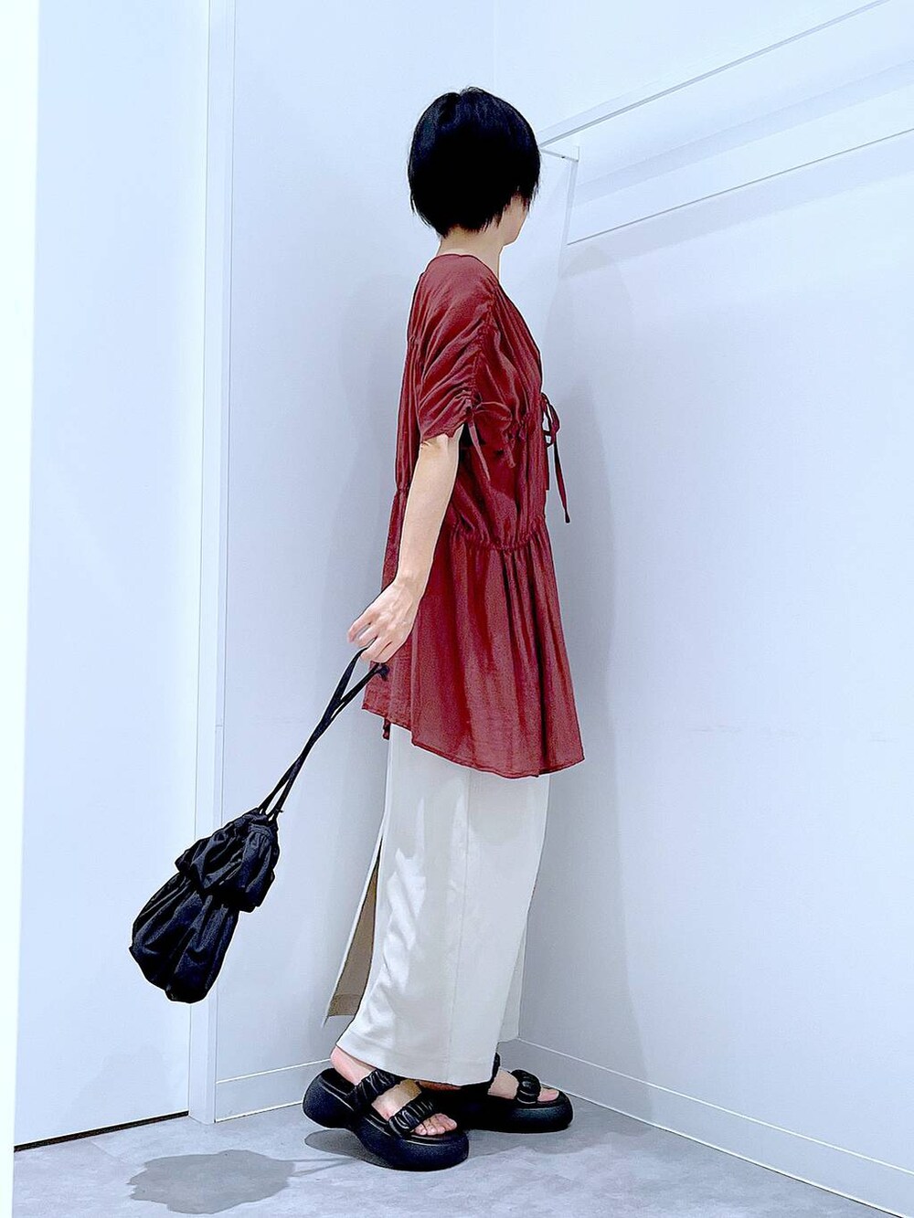 ブラック系のサンダル、ベージュ系のスカート、ブラック系のショルダーバッグを着用したレディースの秋コーディネートの4枚目の写真