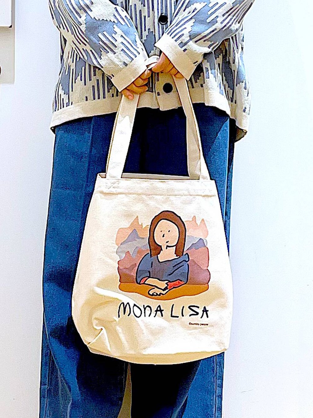 ブルー系のデニムパンツ、ベージュ系のカーディガン/ボレロ、その他のトートバッグを着用したレディースの春コーディネートの9枚目の写真