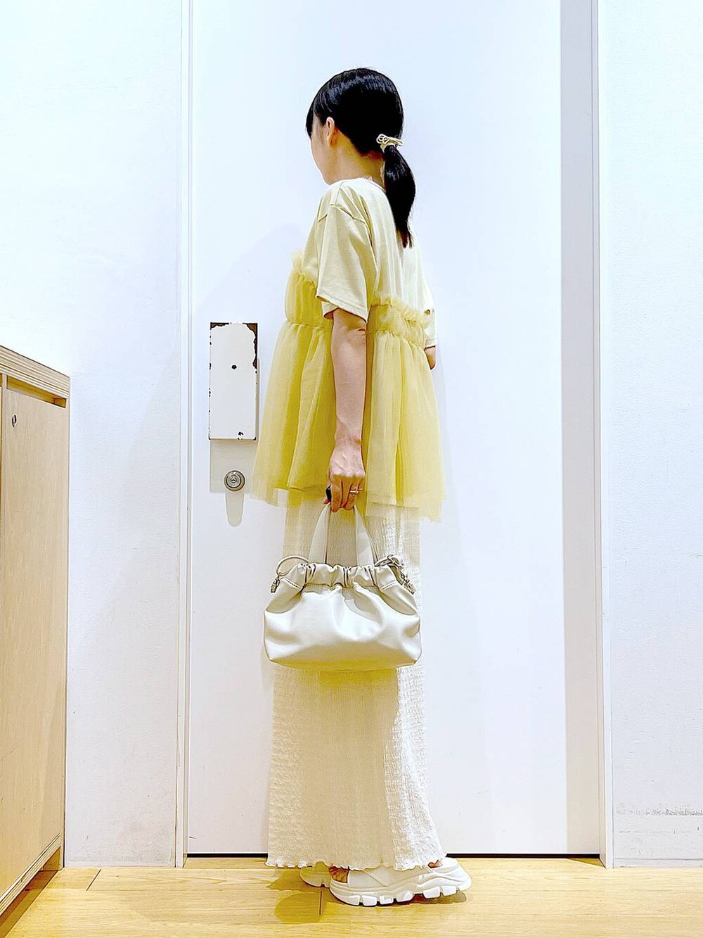 ホワイト系のサンダル、ベージュ系のスカート、イエロー系のTシャツ/カットソーを着用したレディースの夏コーディネートの3枚目の写真