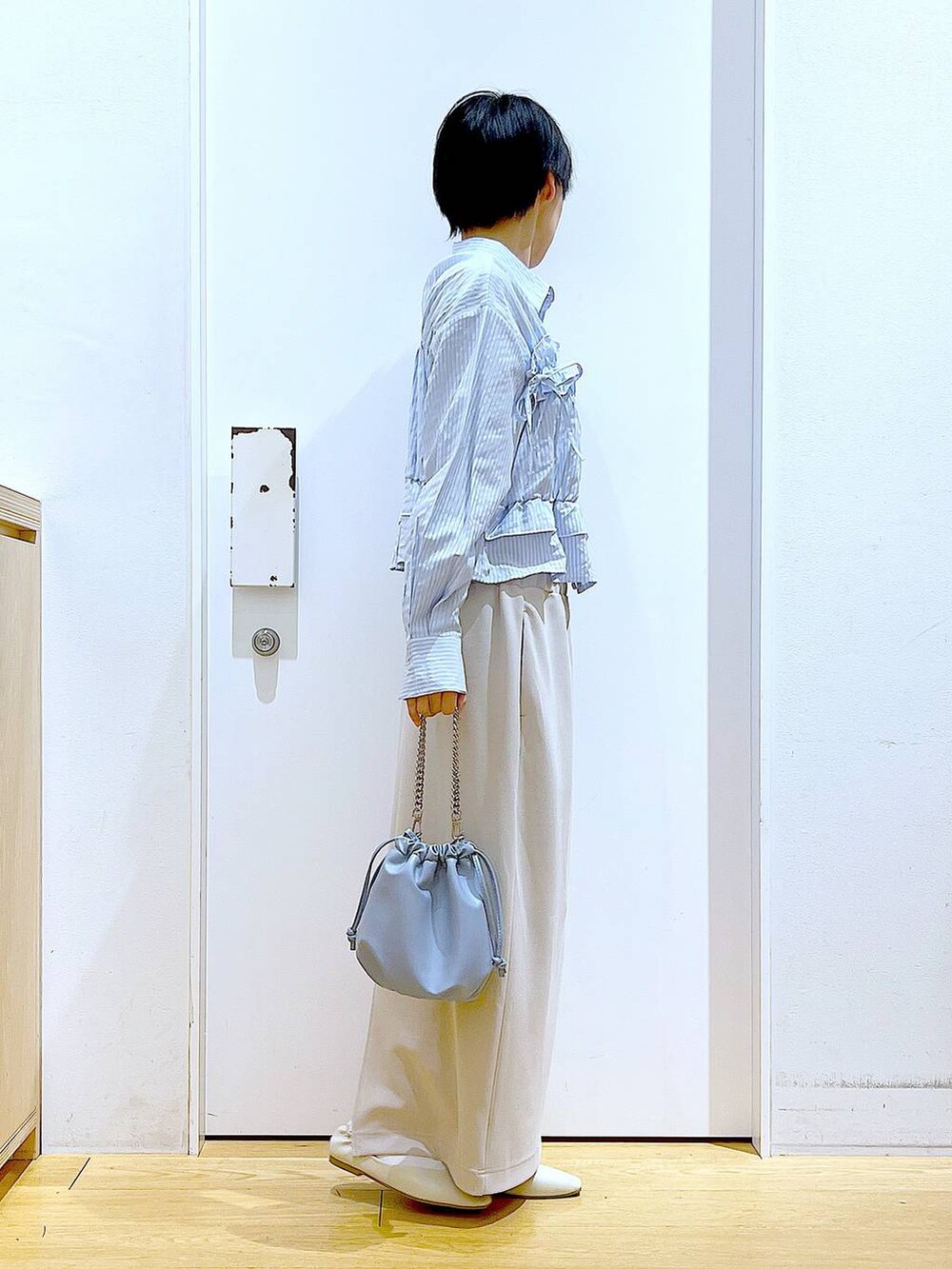 ブルー系のショルダーバッグ、ホワイト系のパンプス、ベージュ系のスカートを着用したレディースの春コーディネートの4枚目の写真