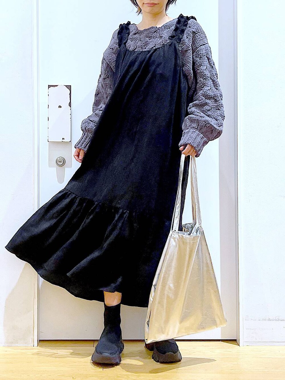 シルバー系のトートバッグ、ブラック系のブーツ、グレー系のニット/セーターを着用したレディースの冬コーディネートの6枚目の写真