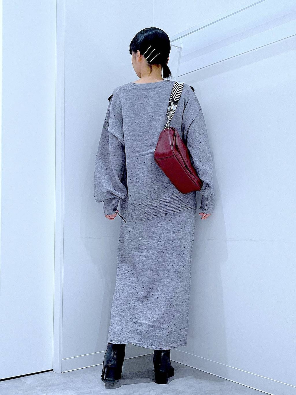 グレー系のニット/セーター、レッド系のショルダーバッグ、グレー系のスカートを着用したレディースの冬コーディネートの5枚目の写真