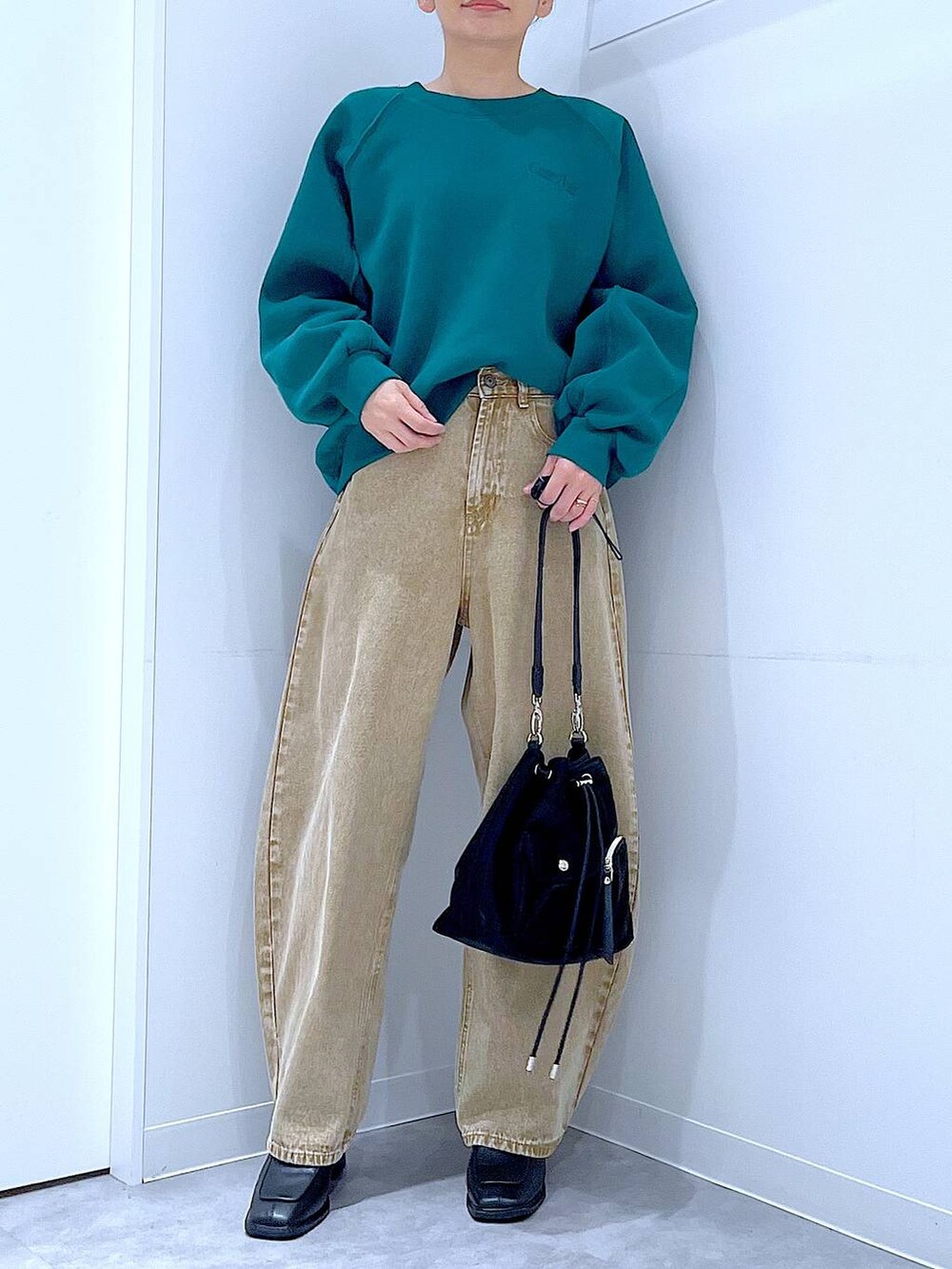 ベージュ系のデニムパンツ、ブラック系のショルダーバッグ、ブラック系のブーツを着用したレディースの冬コーディネートの6枚目の写真