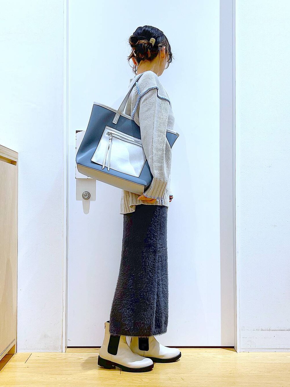 グレー系のトートバッグ、ベージュ系のブーツ、グレー系のスカートを着用したレディースの冬コーディネートの4枚目の写真