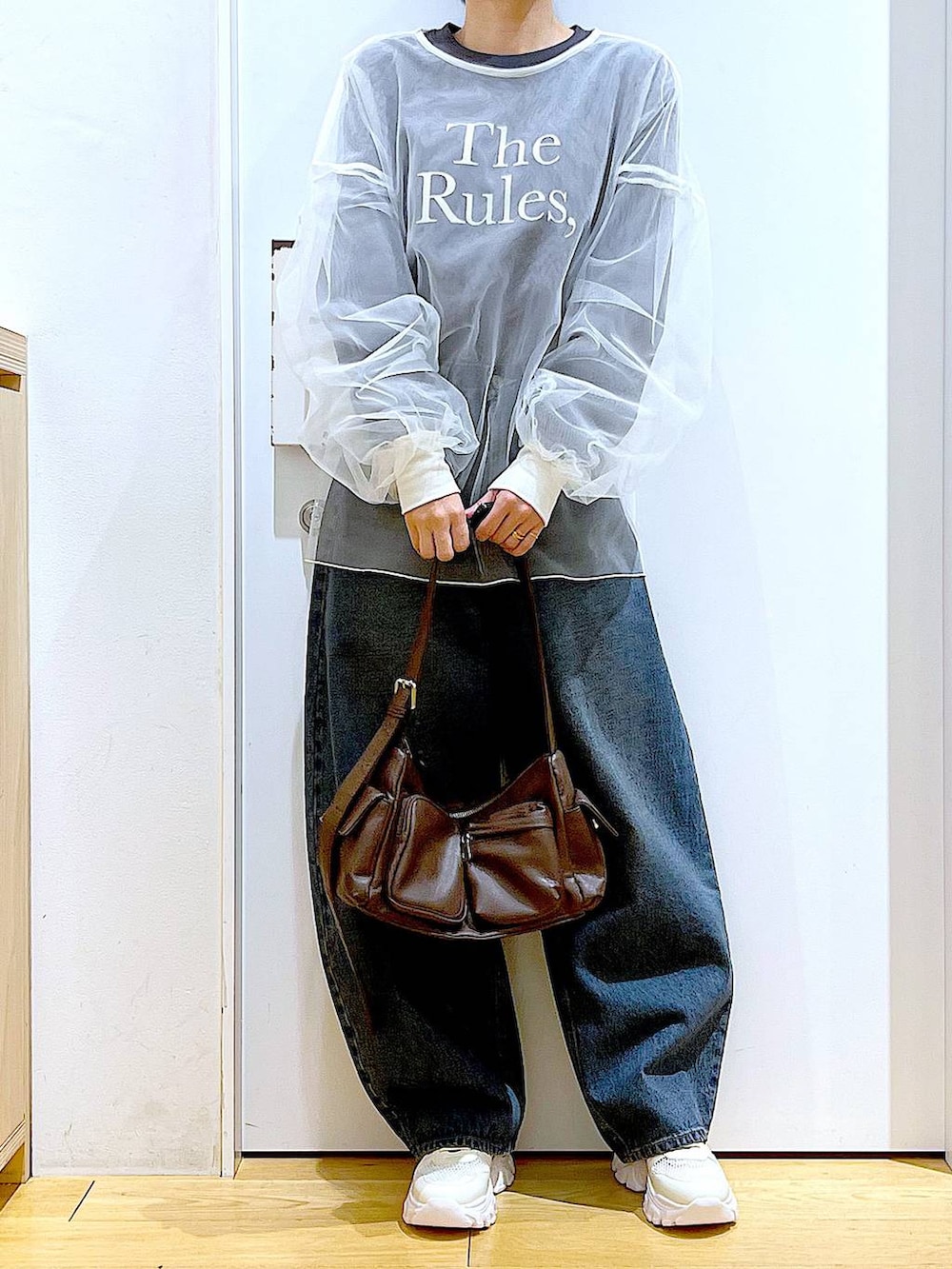 ブルー系のデニムパンツ、ブラウン系のショルダーバッグ、ホワイト系のスニーカーを着用したレディースの春コーディネートの6枚目の写真