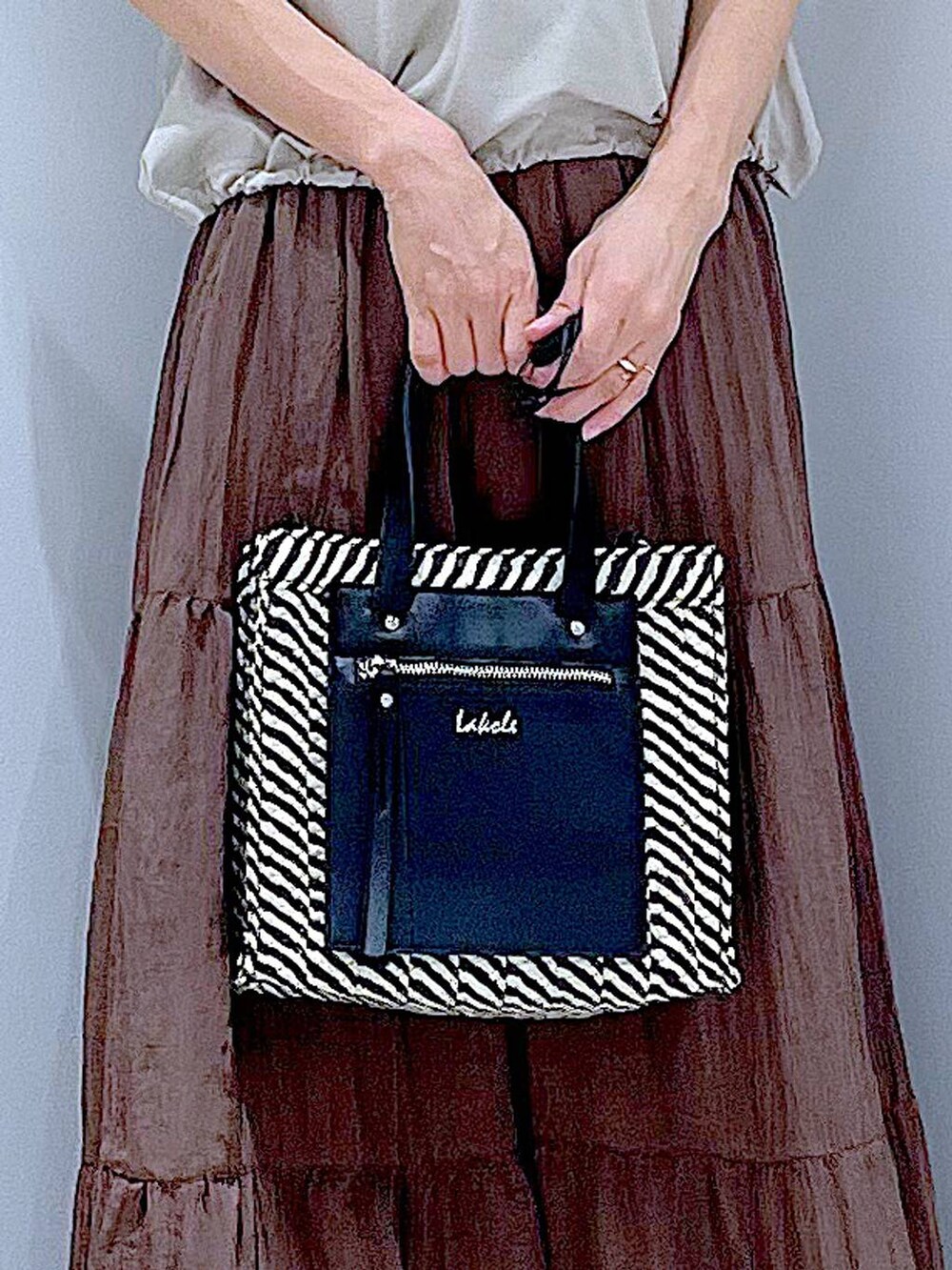 ブラック系のショルダーバッグ、ホワイト系のサンダル、ベージュ系のTシャツ/カットソーを着用したレディースの夏コーディネートの9枚目の写真