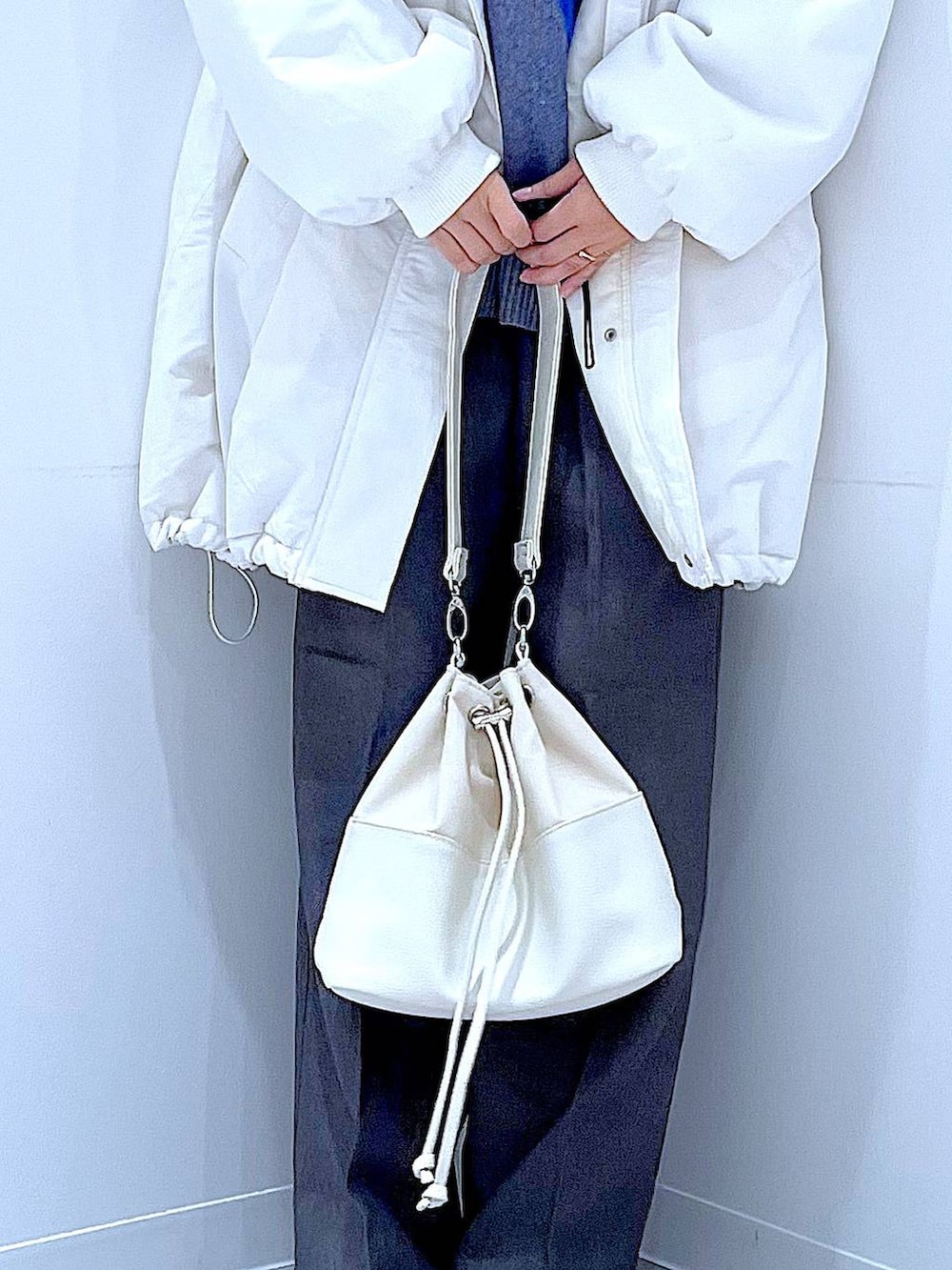 ホワイト系のブルゾン、ホワイト系のショルダーバッグ、ブラック系のブーツを着用したレディースの冬コーディネートの9枚目の写真