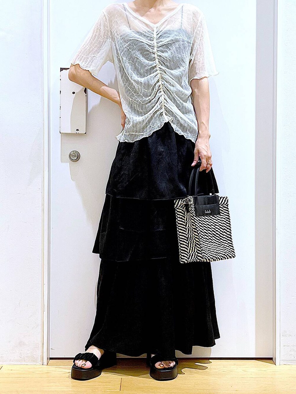 ブラック系のサンダル、ブラック系のショルダーバッグ、ブラック系のスカートを着用したレディースの夏コーディネートの6枚目の写真