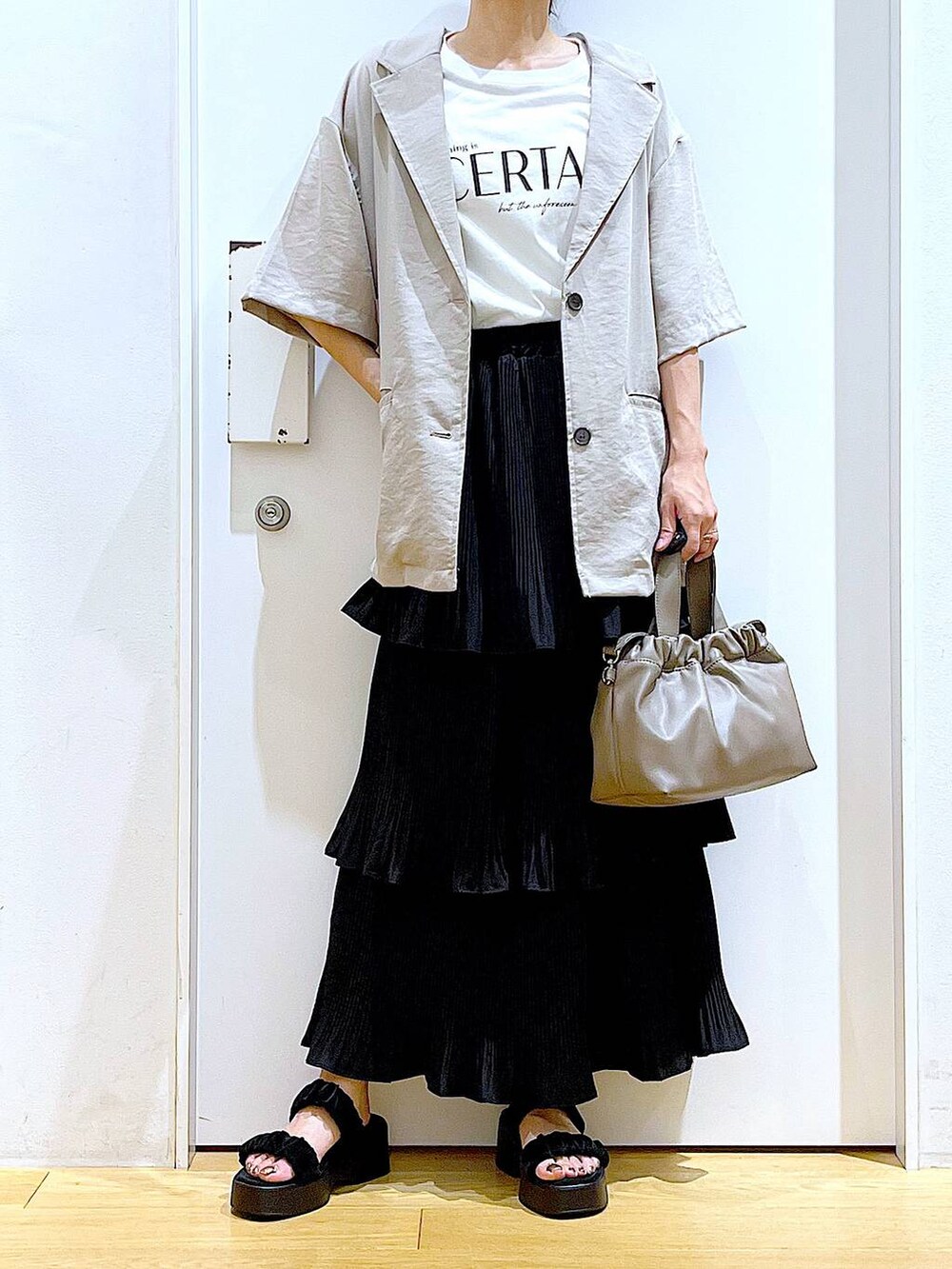 ブラック系のスカート、ブラック系のサンダル、ブラウン系のショルダーバッグを着用したレディースの夏コーディネートの6枚目の写真