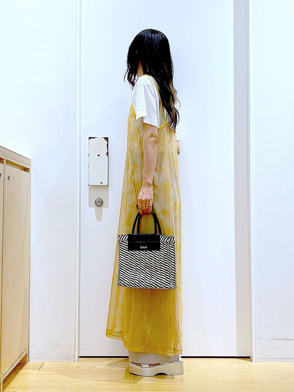 シルバー系のサンダル、オレンジ系のワンピース、ブラック系のショルダーバッグを着用したレディースの夏コーディネートの3枚目の写真