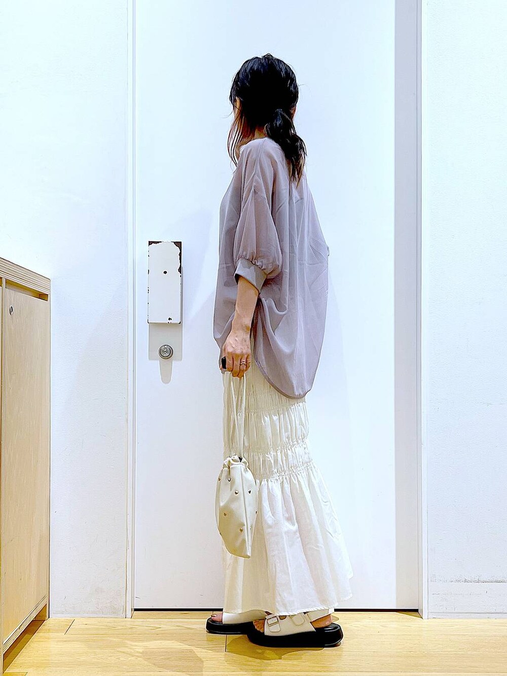 ホワイト系のサンダル、ホワイト系のショルダーバッグ、ホワイト系のスカートを着用したレディースの夏コーディネートの3枚目の写真