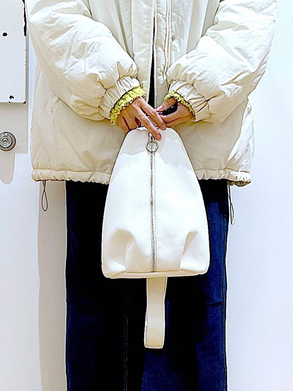 グリーン系のニット/セーター、ブルー系のジャンパースカート、ホワイト系のボディバッグ/ウエストポーチを着用したレディースの冬コーディネートの9枚目の写真