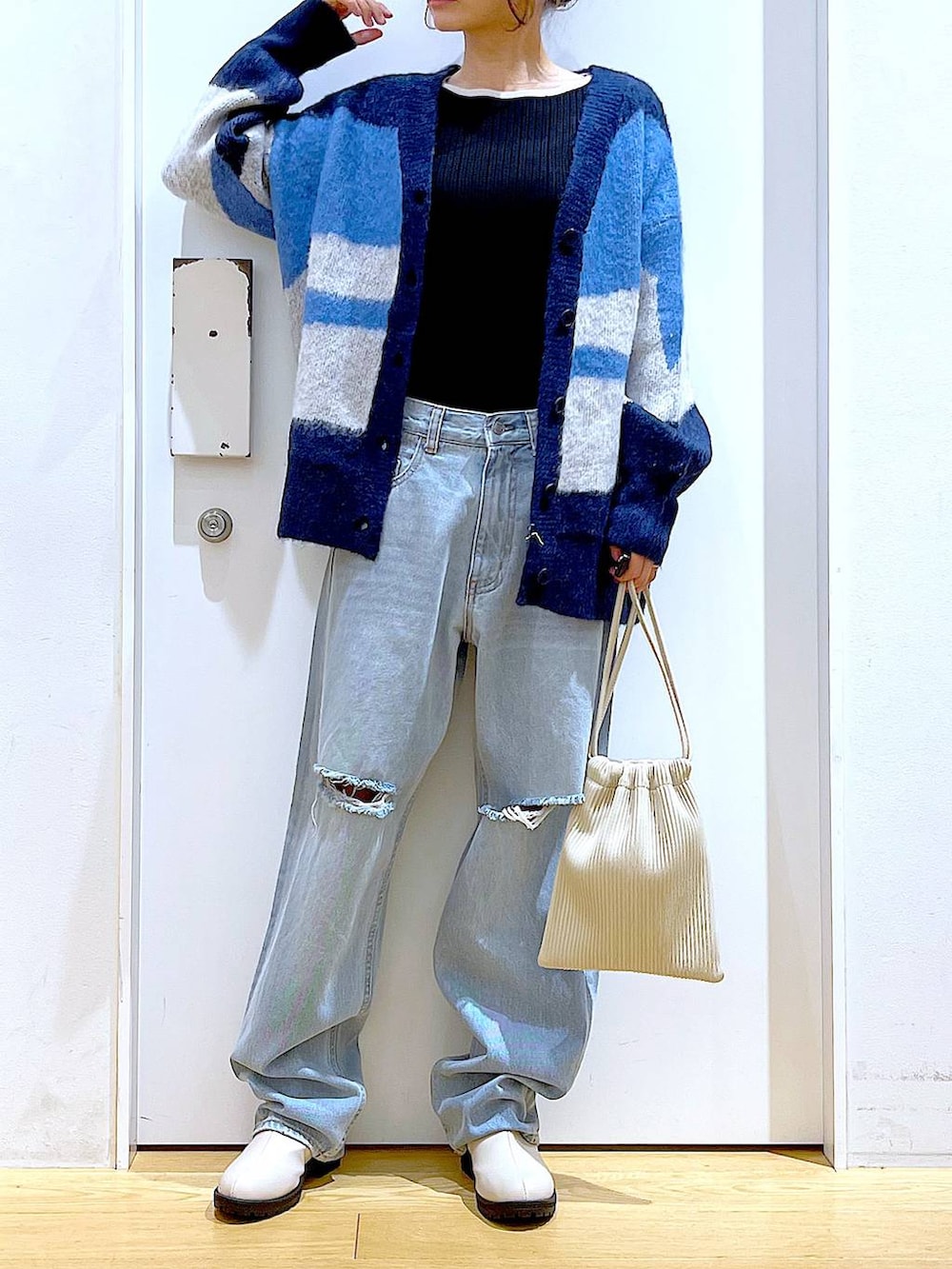 ベージュ系のショルダーバッグ、ベージュ系のブーツ、ブラック系のニット/セーターを着用したレディースの冬コーディネートの6枚目の写真