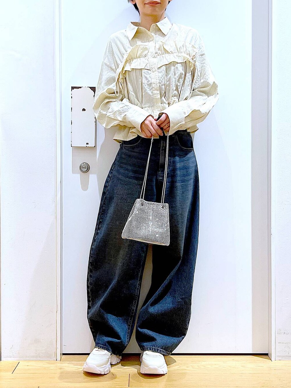 グレー系のショルダーバッグ、ブルー系のデニムパンツ、ホワイト系のスニーカーを着用したレディースの春コーディネートの7枚目の写真