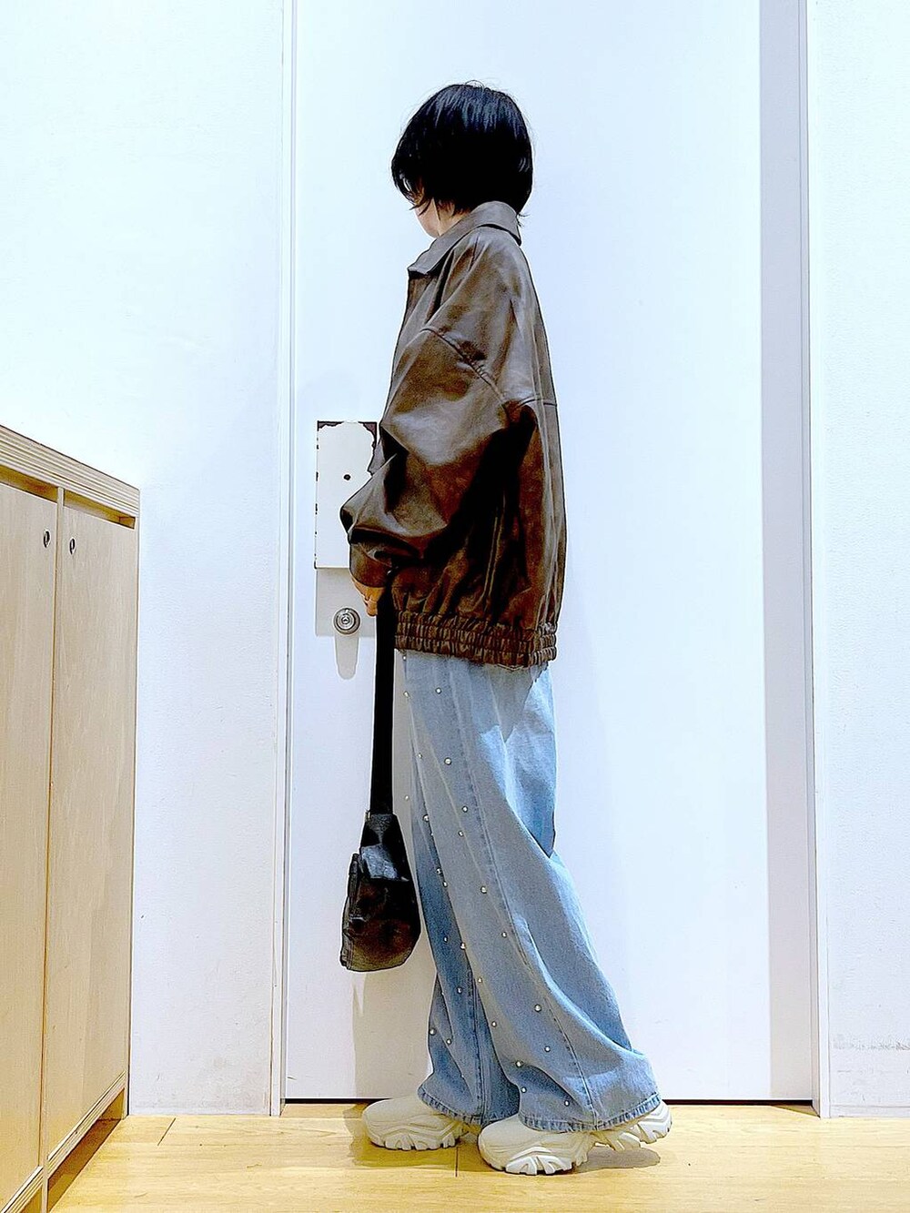 ブラウン系のブルゾン、ベージュ系のブーツ、ブルー系のデニムパンツを着用したレディースの秋コーディネートの3枚目の写真