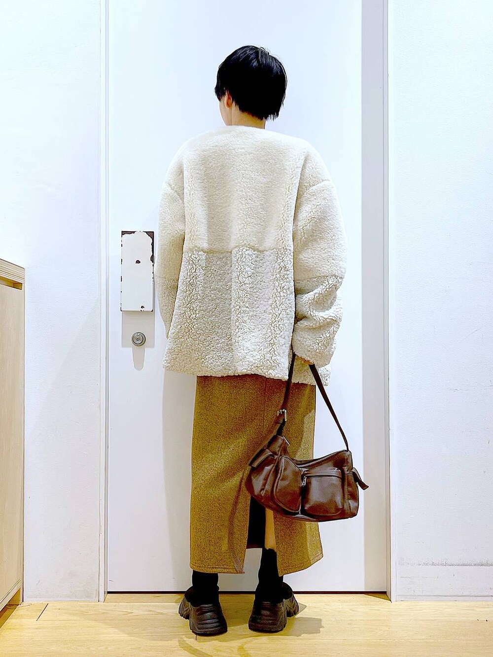 ベージュ系のブルゾン、ブラック系のブーツ、ブラウン系のショルダーバッグを着用したレディースの冬コーディネートの5枚目の写真