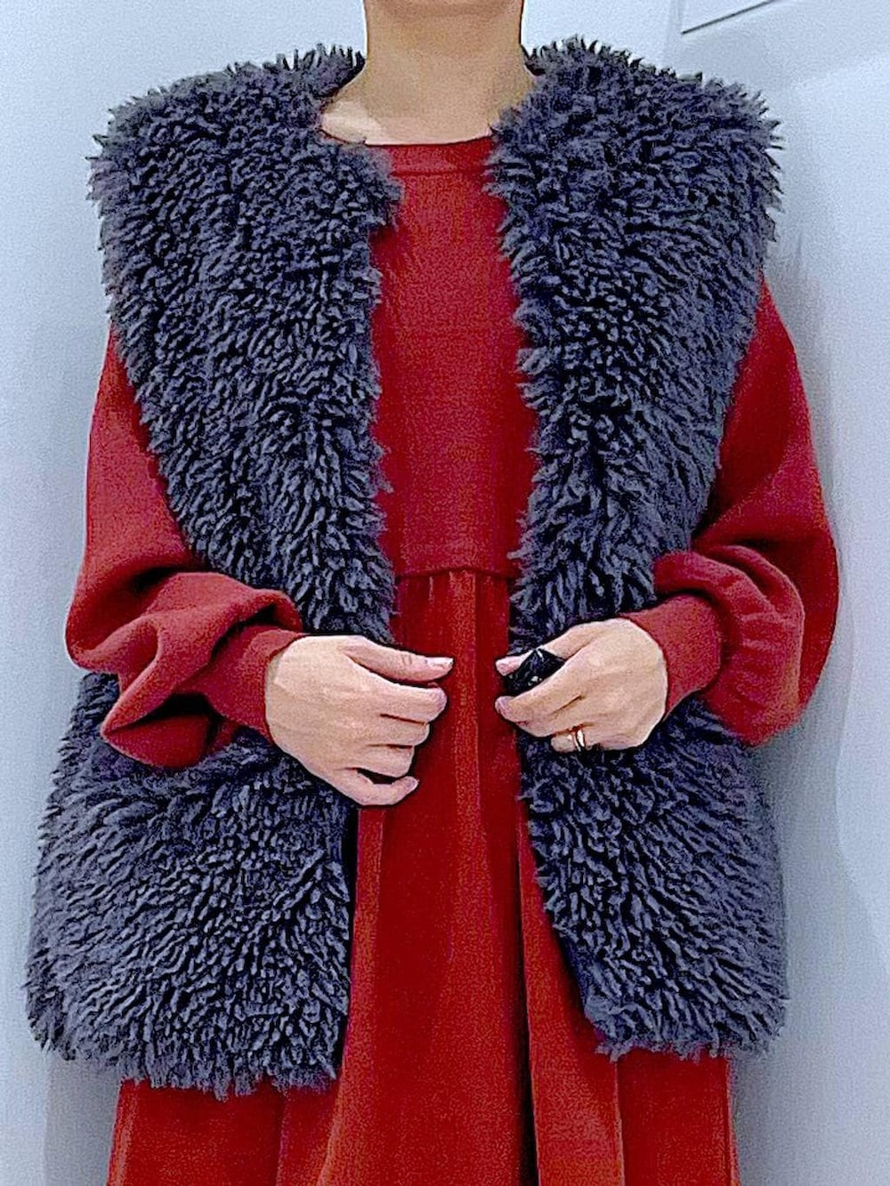 グレー系のベスト、ブラック系のブーツ、ホワイト系のショルダーバッグを着用したレディースの秋コーディネートの7枚目の写真