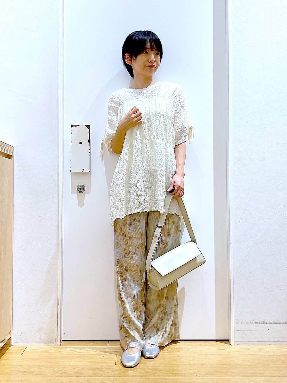 シルバー系のパンプス、ホワイト系のショルダーバッグ、ベージュ系のその他パンツを着用したレディースの春コーディネートの2枚目の写真