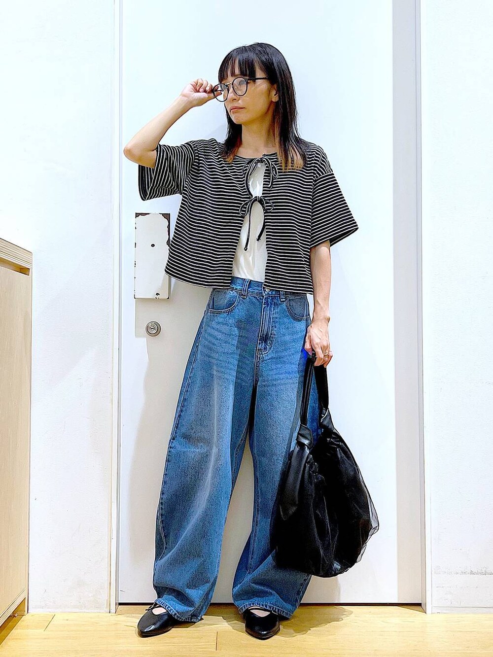 ブラック系のトートバッグ、ブルー系のデニムパンツ、その他のカーディガン/ボレロを着用したレディースの秋コーディネートの2枚目の写真