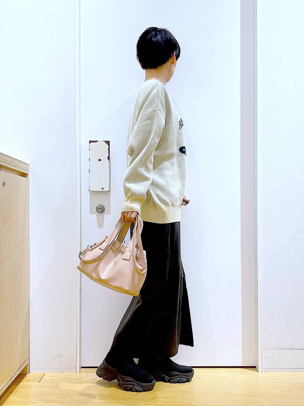 ブラック系のスカート、ブラック系のブーツ、ピンク系のショルダーバッグを着用したレディースの冬コーディネートの4枚目の写真