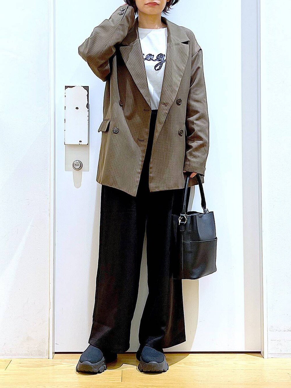 ブラック系のブーツ、ブラック系のショルダーバッグ、ブラウン系のテーラードジャケットを着用したレディースの秋コーディネートの6枚目の写真