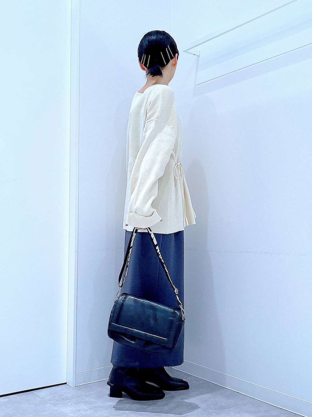 グレー系のスカート、ブラック系のショルダーバッグ、ブラック系のブーツを着用したレディースの冬コーディネートの4枚目の写真