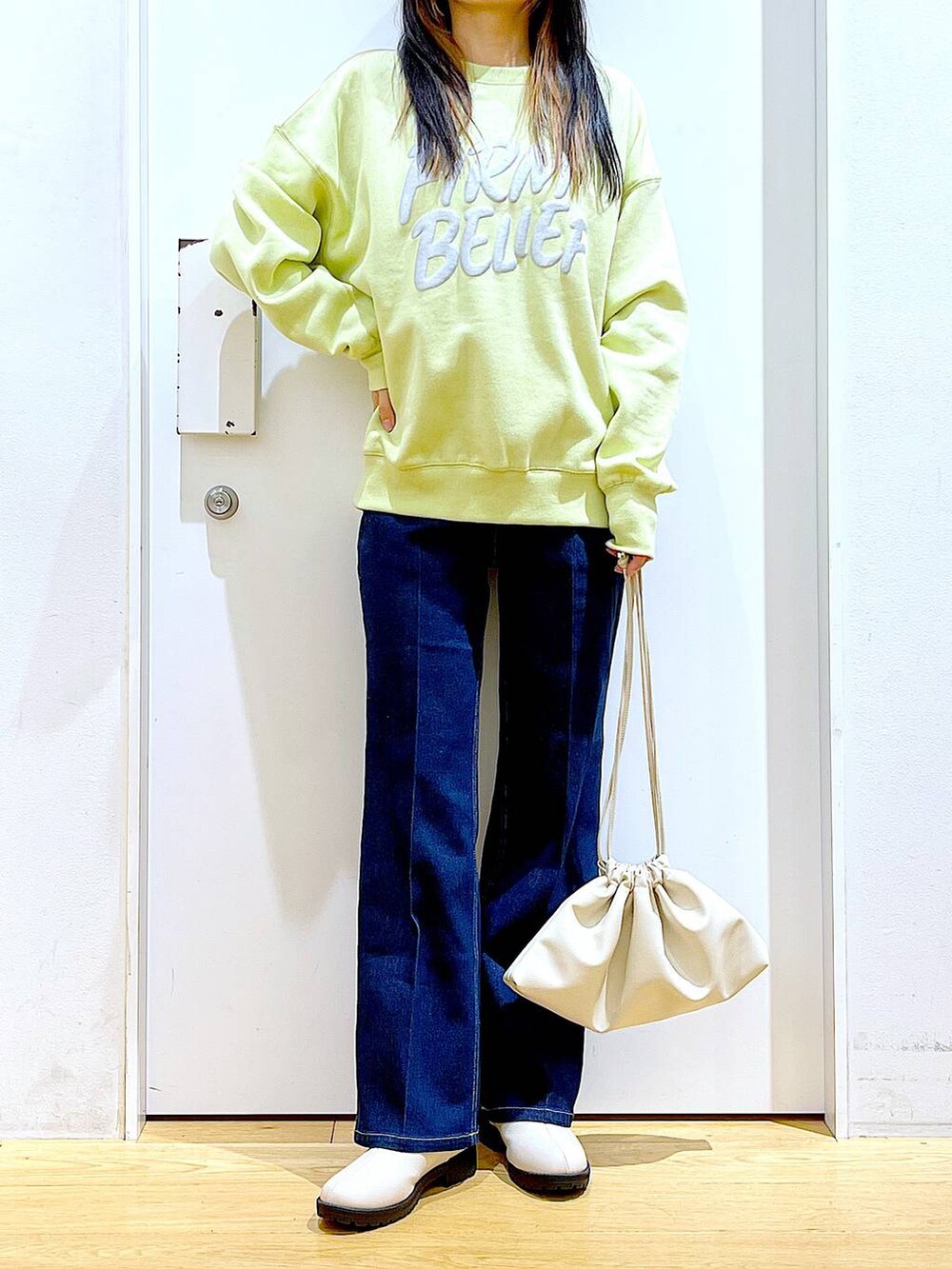 ブルー系のデニムパンツ、イエロー系のスウェット、ベージュ系のブーツを着用したレディースの冬コーディネートの6枚目の写真