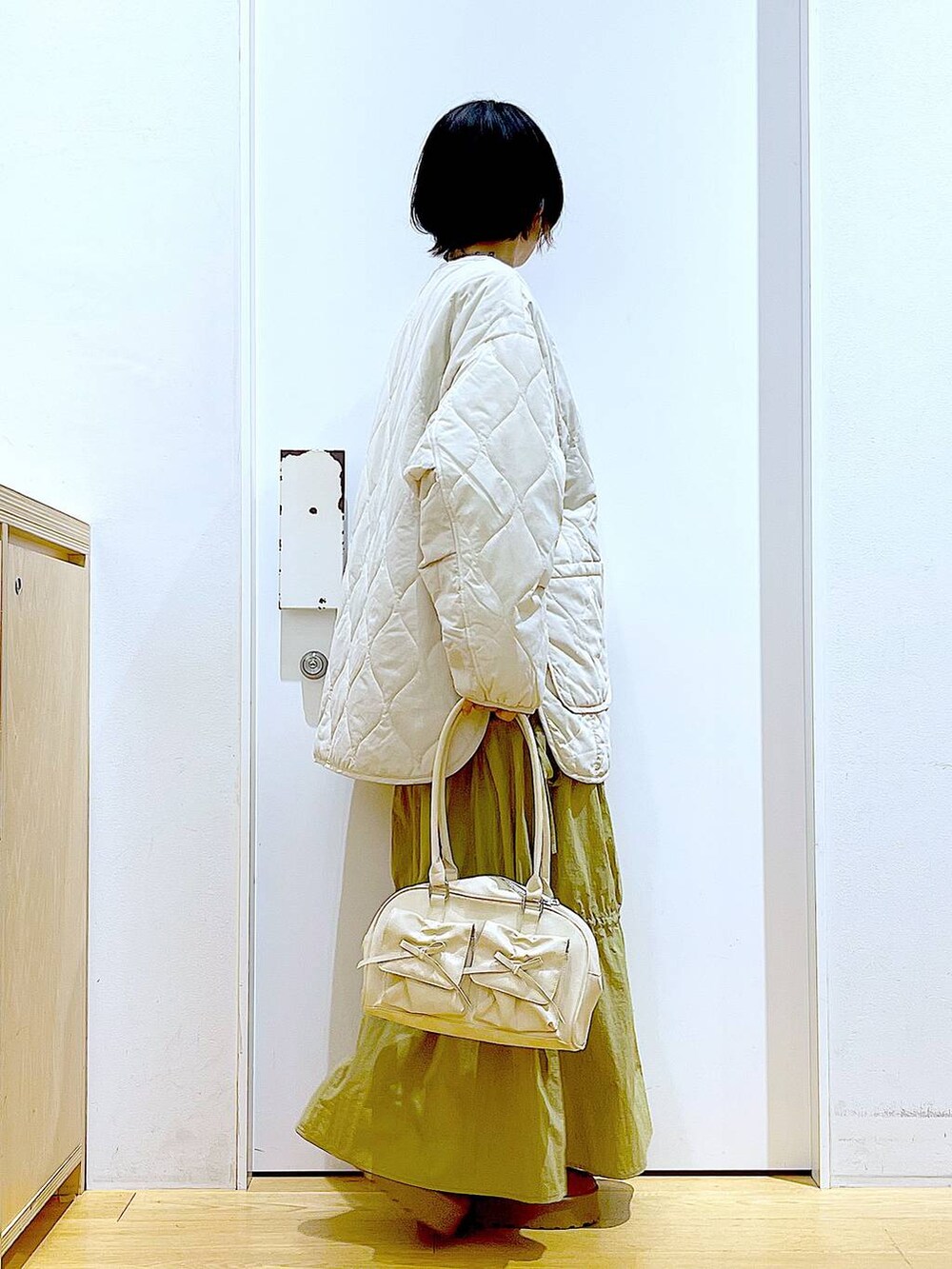 ベージュ系のブルゾン、ベージュ系のスリッポン、ホワイト系のハンドバッグを着用したレディースの秋コーディネートの4枚目の写真