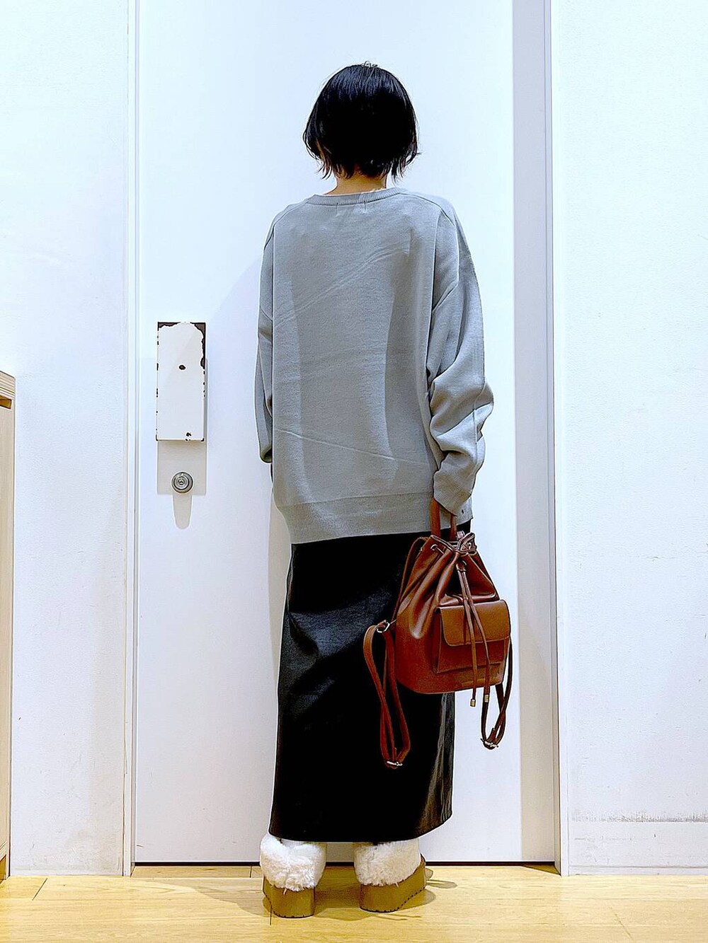 グレー系のニット/セーター、ブラウン系のバックパック/リュック、ブラック系のスカートを着用したレディースの冬コーディネートの5枚目の写真