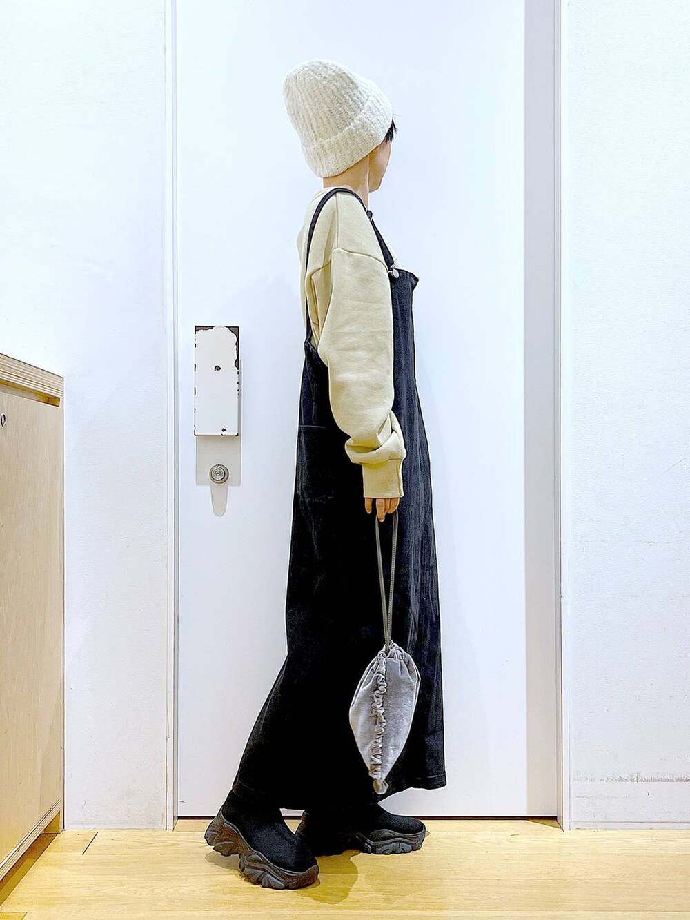 グレー系のジャンパースカート、グレー系のショルダーバッグ、ブラック系のブーツを着用したレディースの冬コーディネートの4枚目の写真