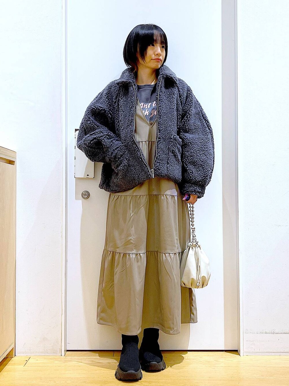 ベージュ系のショルダーバッグ、ブラック系のブーツ、ブラウン系のワンピースを着用したレディースの冬コーディネートの2枚目の写真