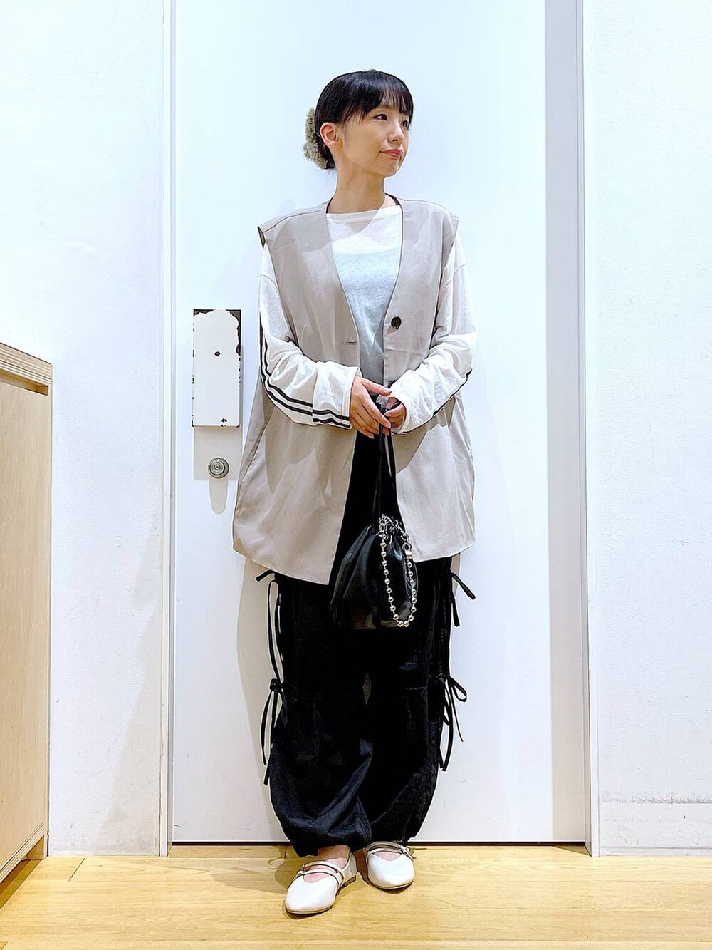 ブラック系のショルダーバッグ、ホワイト系のパンプス、ブラック系のその他パンツを着用したレディースの秋コーディネートの2枚目の写真