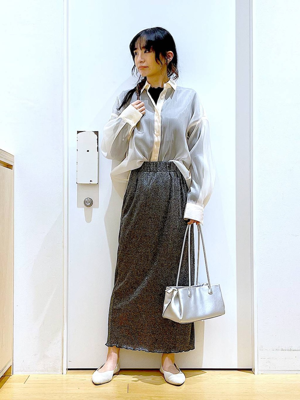 ブラック系のスカート、ホワイト系のパンプス、ホワイト系のシャツ/ブラウスを着用したレディースの春コーディネートの2枚目の写真