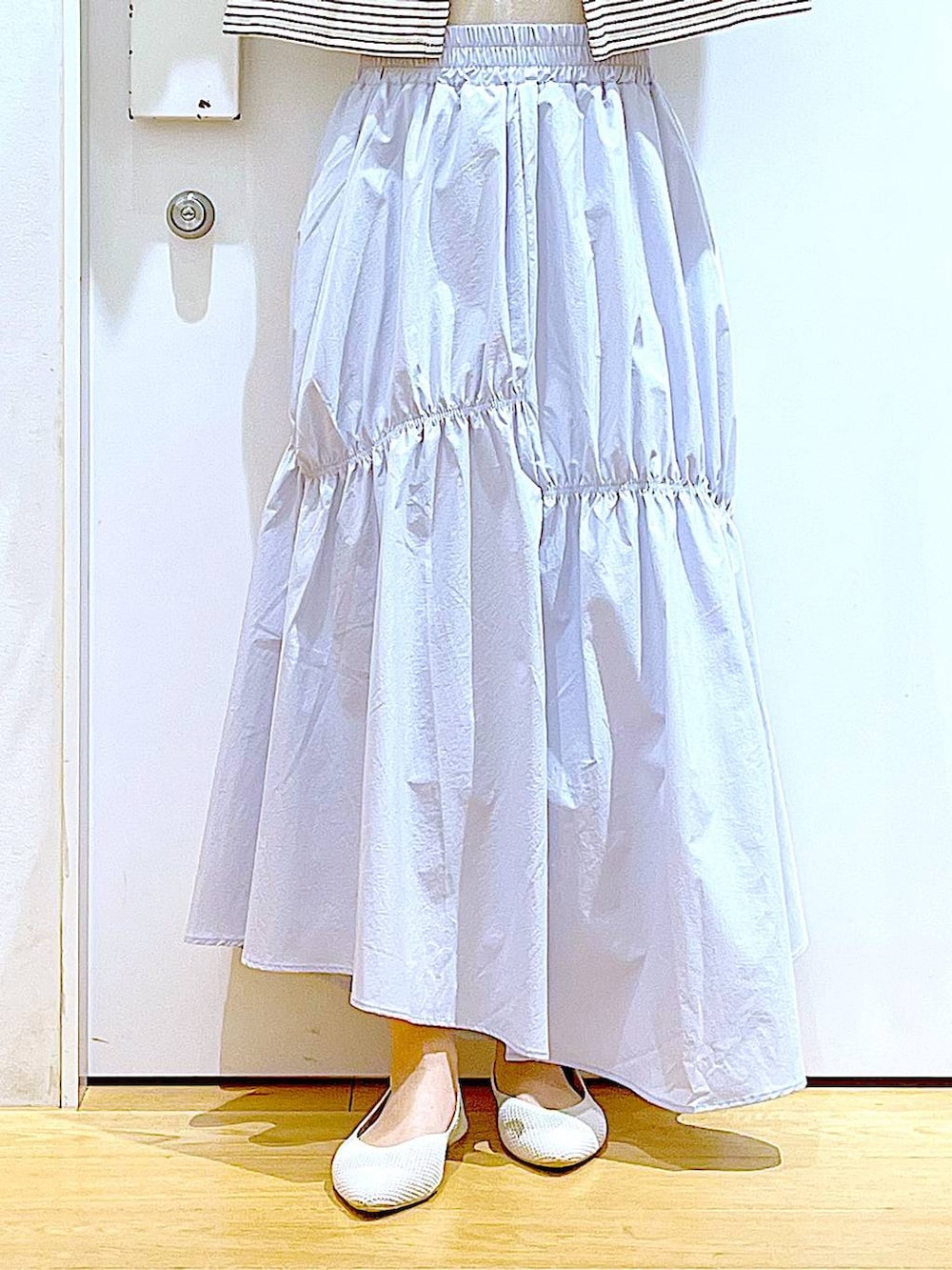 ブラック系のトートバッグ、ブルー系のスカート、イエロー系のニット/セーターを着用したレディースの春コーディネートの8枚目の写真