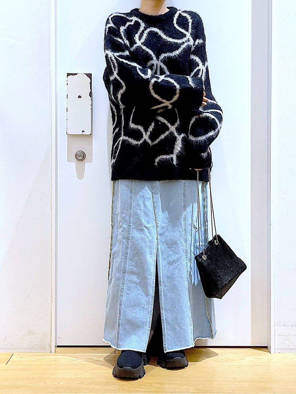 ブルー系のデニムスカート、ブラック系のブーツ、ブラック系のショルダーバッグを着用したレディースの冬コーディネートの6枚目の写真