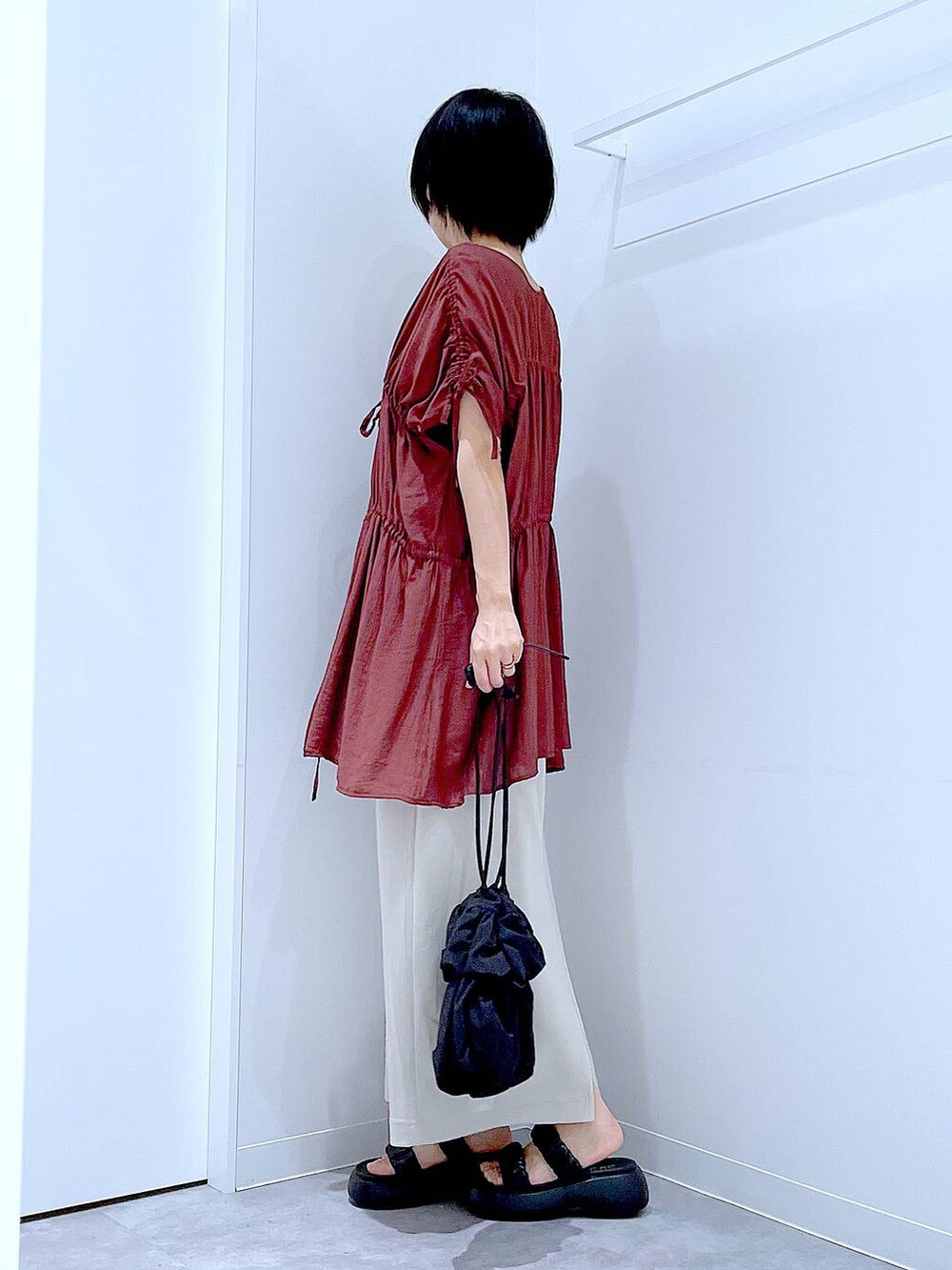 ブラック系のサンダル、ベージュ系のスカート、ブラック系のショルダーバッグを着用したレディースの秋コーディネートの3枚目の写真