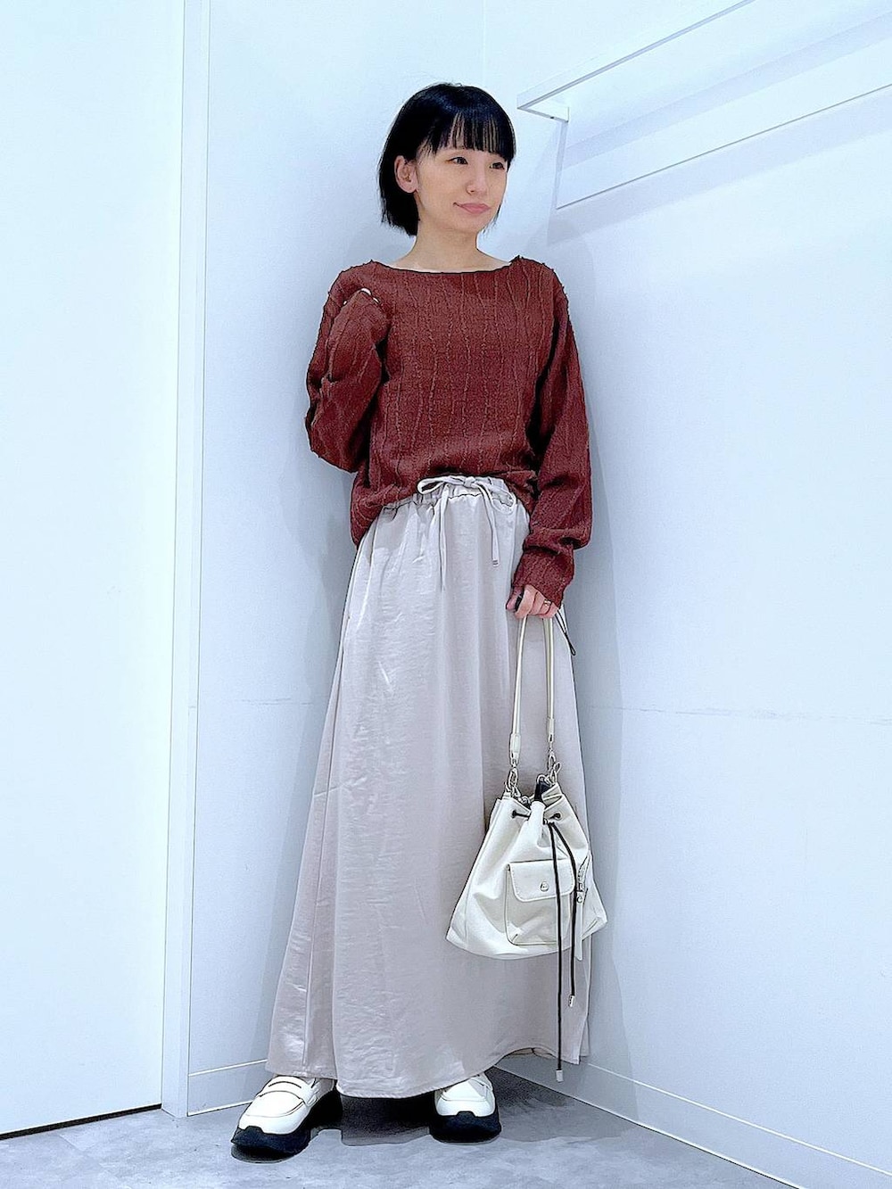 ホワイト系のローファー、ホワイト系のショルダーバッグ、ベージュ系のスカートを着用したレディースの秋コーディネートの2枚目の写真
