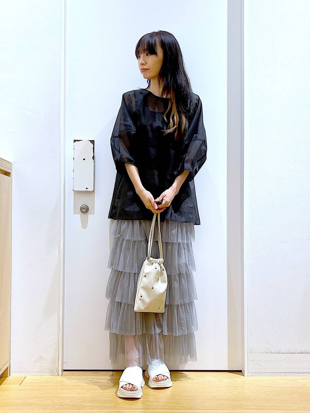 ホワイト系のサンダル、ブラック系のニット/セーター、ホワイト系のショルダーバッグを着用したレディースの夏コーディネートの2枚目の写真