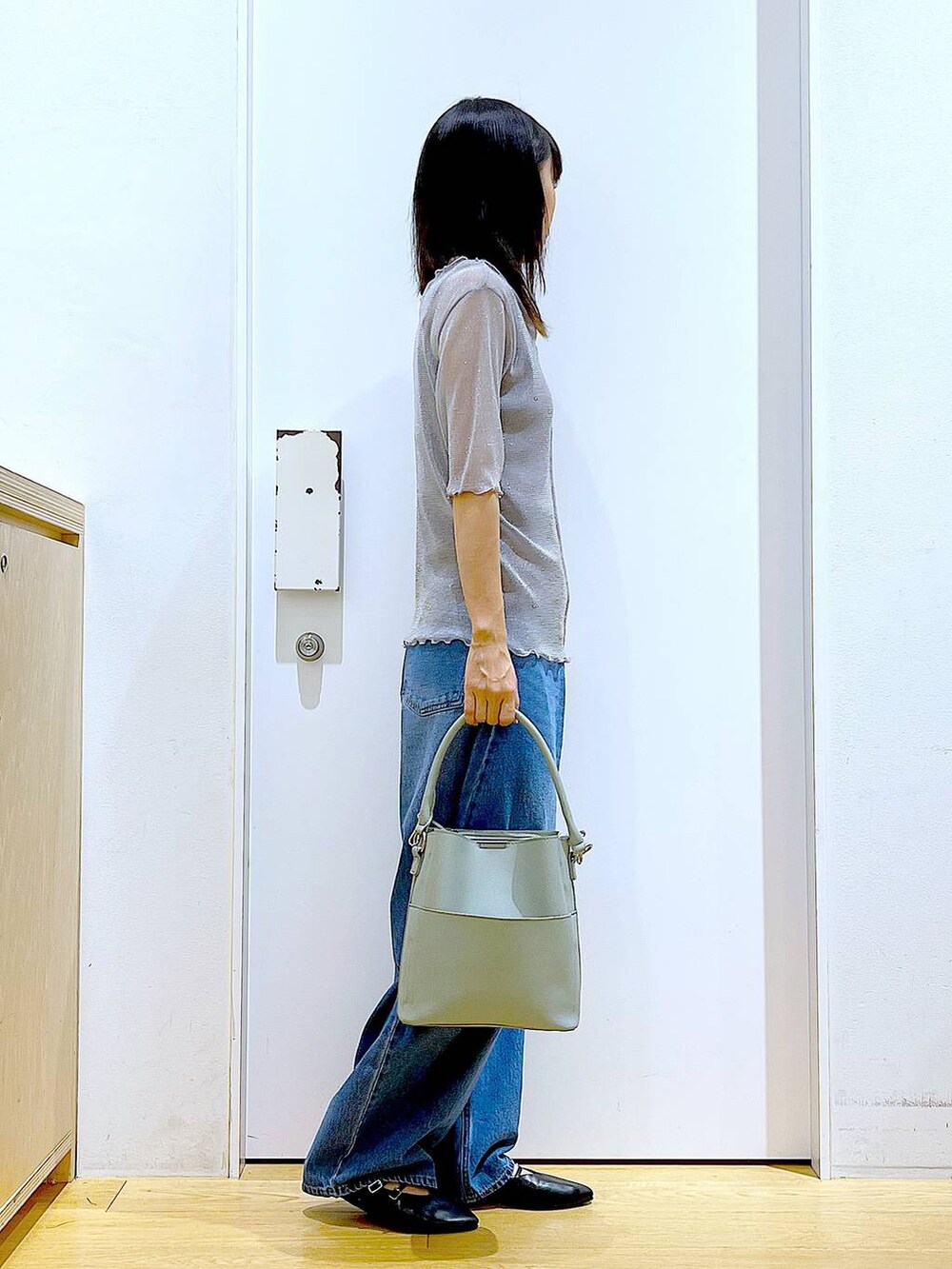 グレー系のTシャツ/カットソー、ブルー系のデニムパンツ、グリーン系のショルダーバッグを着用したレディースの秋コーディネートの4枚目の写真