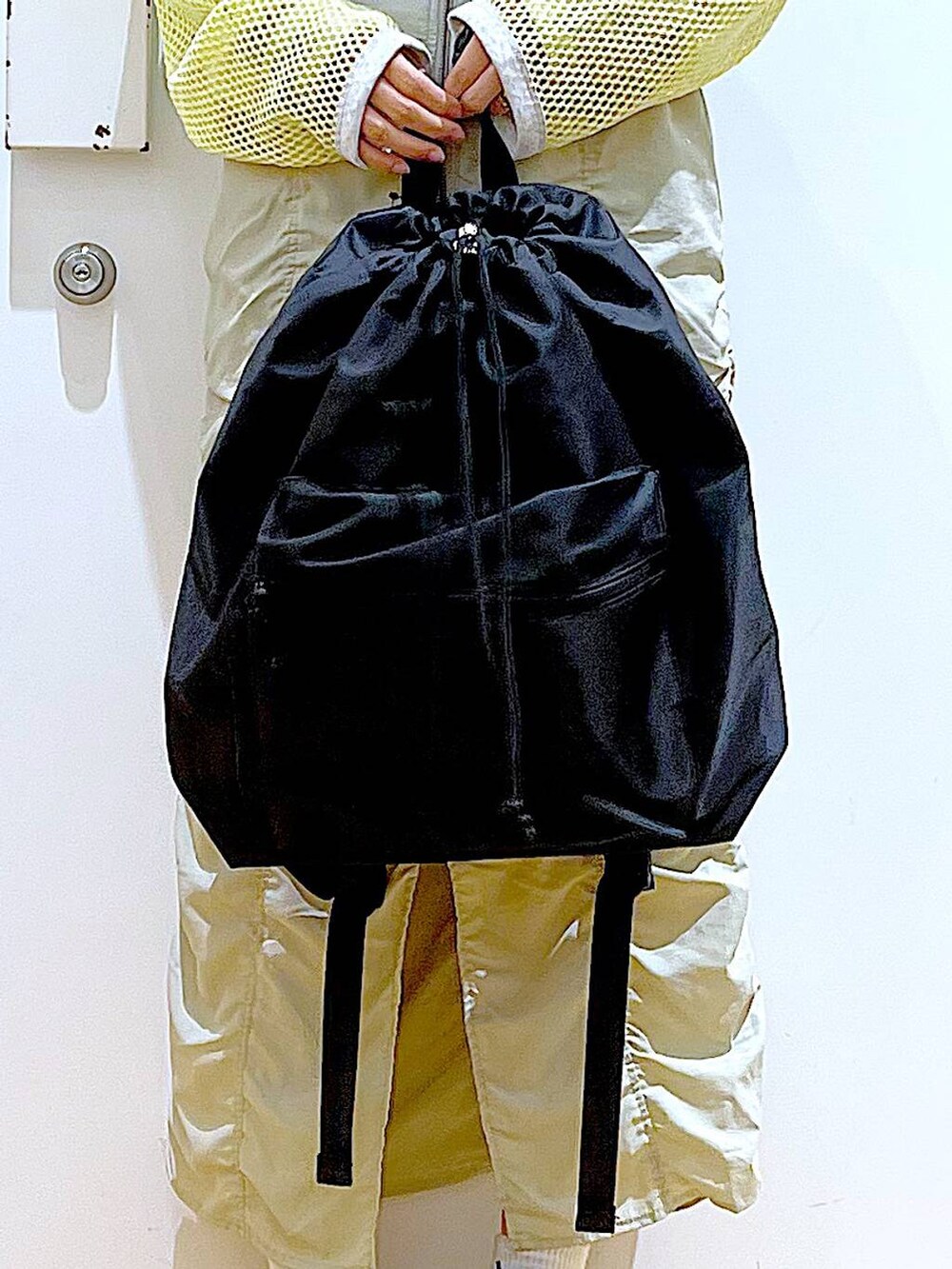 ベージュ系のスカート、ブラック系のバックパック/リュック、イエロー系のTシャツ/カットソーを着用したレディースの春コーディネートの9枚目の写真