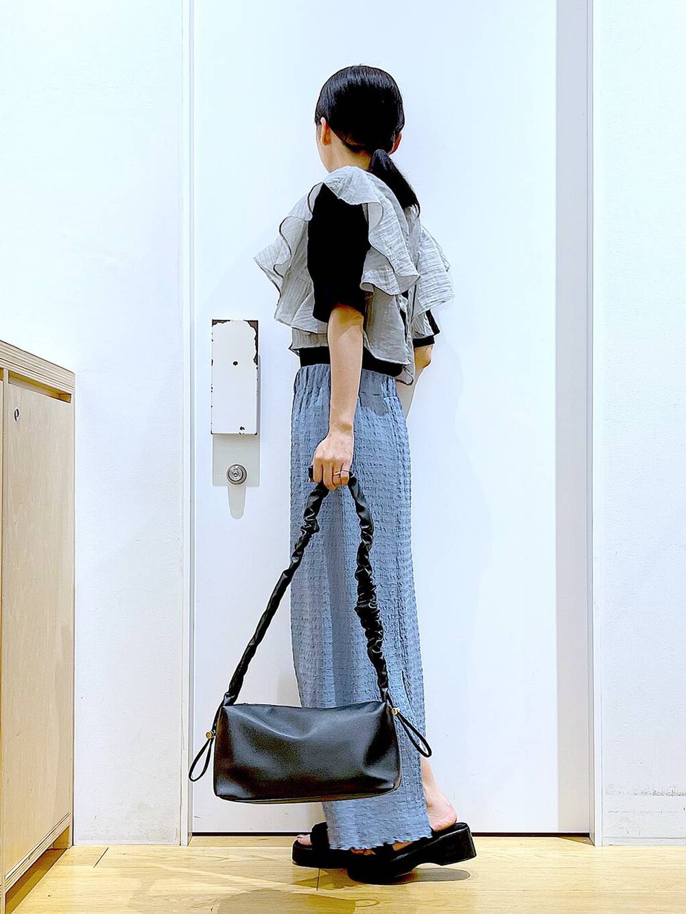 ブラック系のショルダーバッグ、ブルー系のスカート、ブラック系のTシャツ/カットソーを着用したレディースの夏コーディネートの3枚目の写真