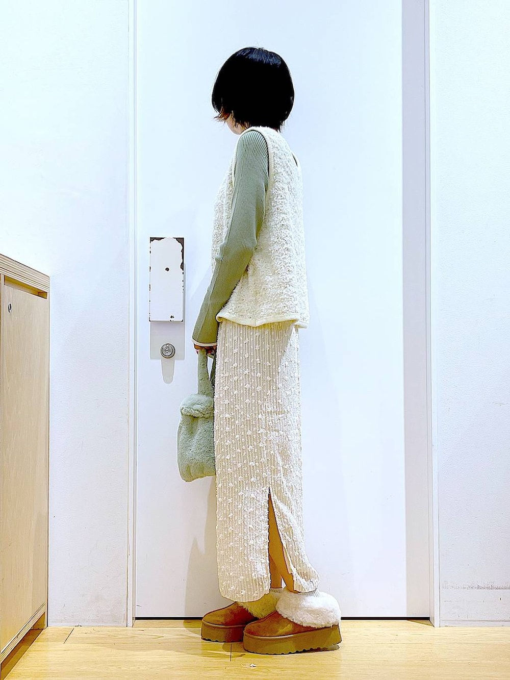 グリーン系のニット/セーター、グリーン系のショルダーバッグ、ベージュ系のベストを着用したレディースの秋コーディネートの3枚目の写真